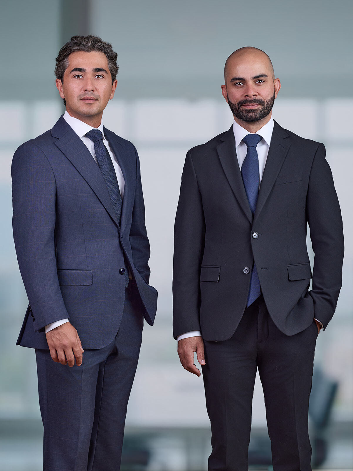 Aidin and Bassem standing next to each other in front of a blurred commerce background.